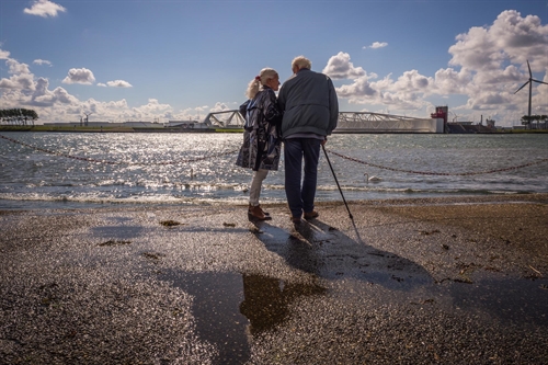 Een koppel langs het water met op de achtergrond de Maeslantkering