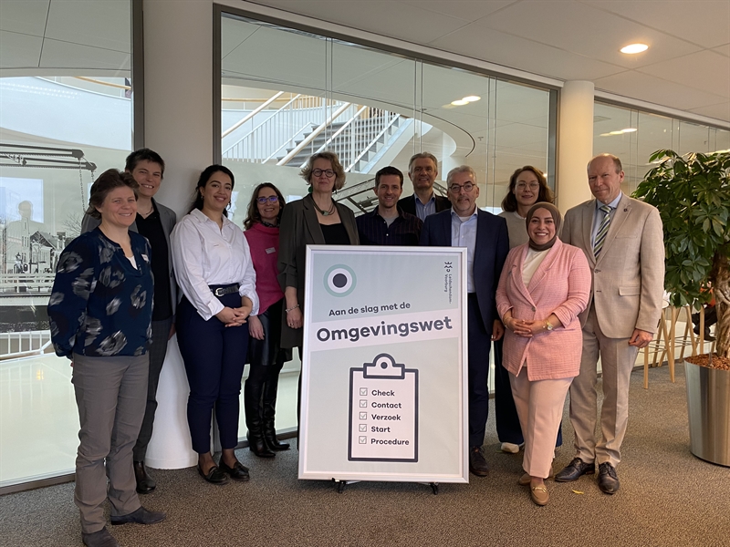 Op de afbeelding staat programma-DG Marjolein Jansen achter een bord met de tekst 'Aan de slag met de Omgevingswet' en 'check, contact, verzoek, start, procedure'. Links naast programma-DG Marjolein Jansen staat Kristel Rijpert (projectleider Omgevingswet), aan de andere kant van Jansen staat Niek Huis in ’t Veld (projectleider Omgevingswet) naast Huis in ‘t Veld staat interim-directeur Marcel Schuring, vooraan staat Meryem Tas (jurist Ruimtelijke plannen) en aan de rechterkant staat wethouder Philip van Veller (Financiën, Grondzaken en vastgoed, Regionale samenwerking, Omgevingswet en omgevingsvisie, Inkomen, armoedebestrijding en schuldhulpverlening).
