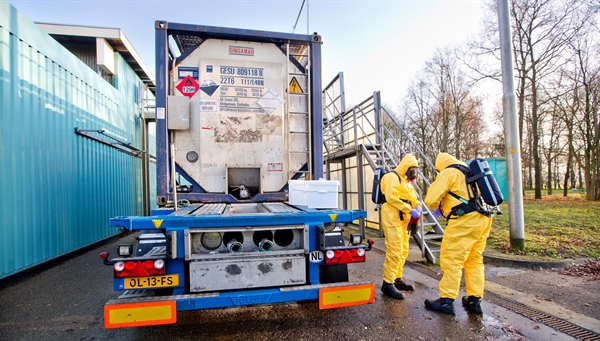 Een vrachtauto met een gevaarlijke stof, met ernaast 2 mensen in gele veiligheidspakken die een monster van een stof nemen