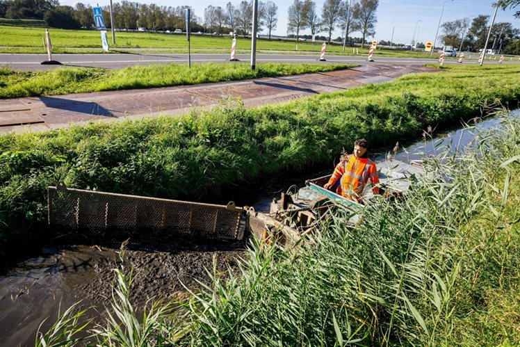 Een baggervaartuig vaart door een sloot