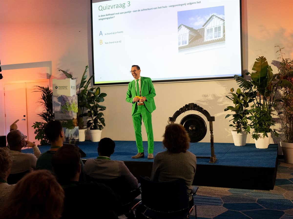 Presentator op het podium tijdens kennisquiz