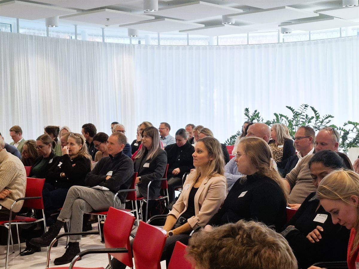 Blik op deelnemers die aandachtig zitten te luisteren.