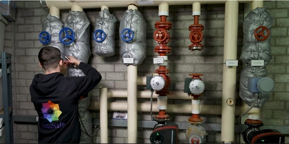 Foto van het aanbrengen van isolatiemateriaal rond leidingen en appendages. Met toestemming van InsulSafe.
