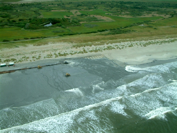 Kust van Ameland met voertuigen die op het strand rijden voor zandsuppletie